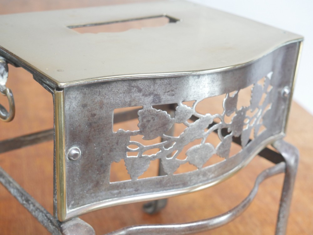 A small Georgian brass and steel footman featuring a top handle slot, side ring handles, and a pierced decorative front apron raised on shaped legs. View IV