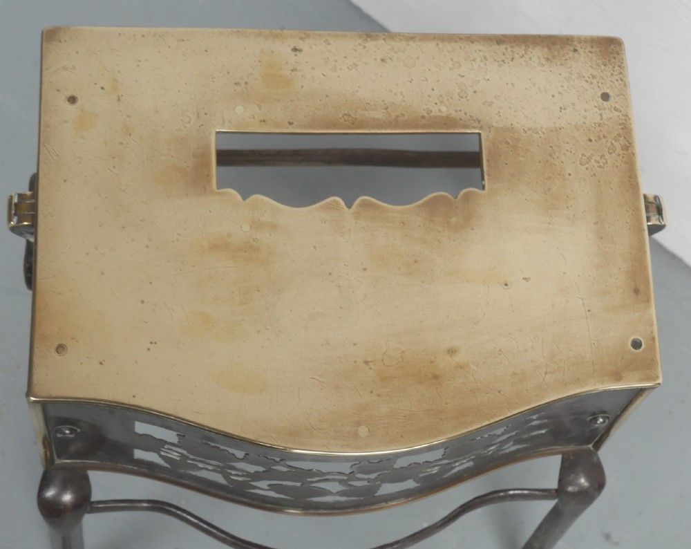 A small Georgian brass and steel footman featuring a top handle slot, side ring handles, and a pierced decorative front apron raised on shaped legs. View V