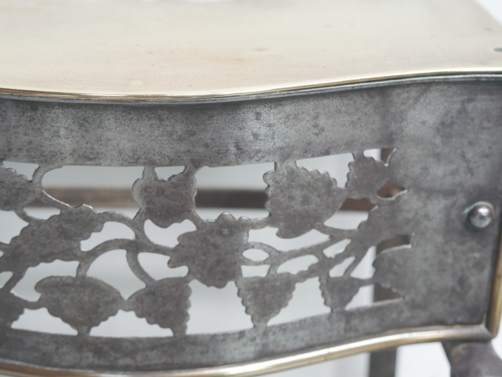 A small Georgian brass and steel footman featuring a top handle slot, side ring handles, and a pierced decorative front apron raised on shaped legs. View VII