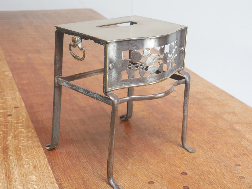 A small Georgian brass and steel footman featuring a top handle slot, side ring handles, and a pierced decorative front apron raised on shaped legs. View IX