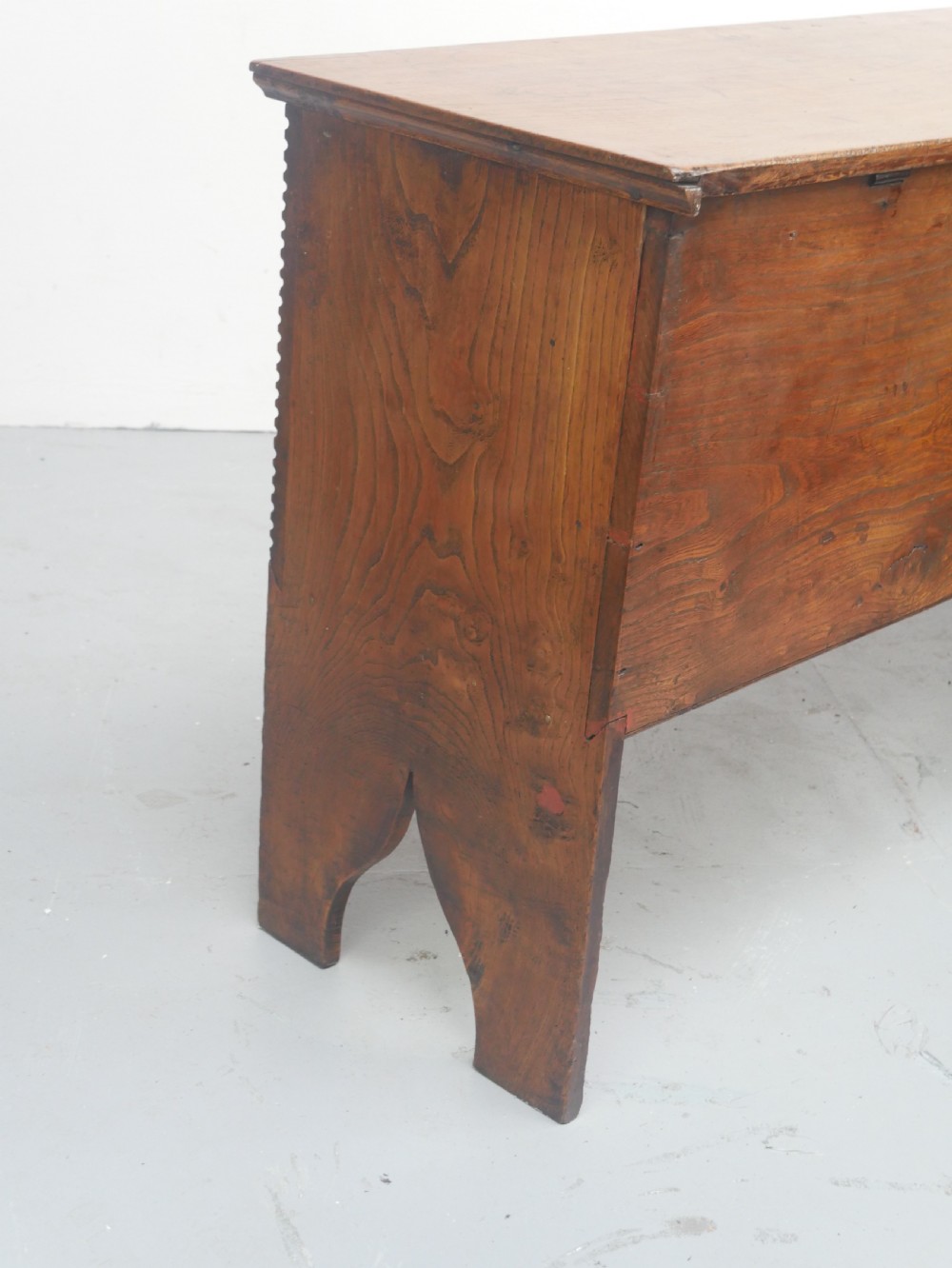 An antique timber six-plank coffer crafted from warm brown elm featuring a central brass keyhole escutcheon and shaped bootjack side panels. View VIII