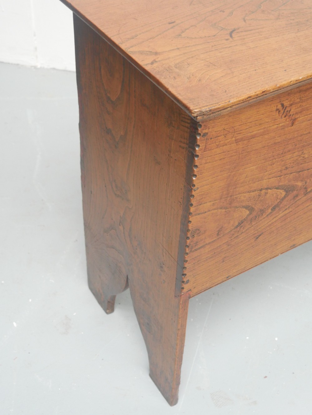 An antique timber six-plank coffer crafted from warm brown elm featuring a central brass keyhole escutcheon and shaped bootjack side panels. View IX