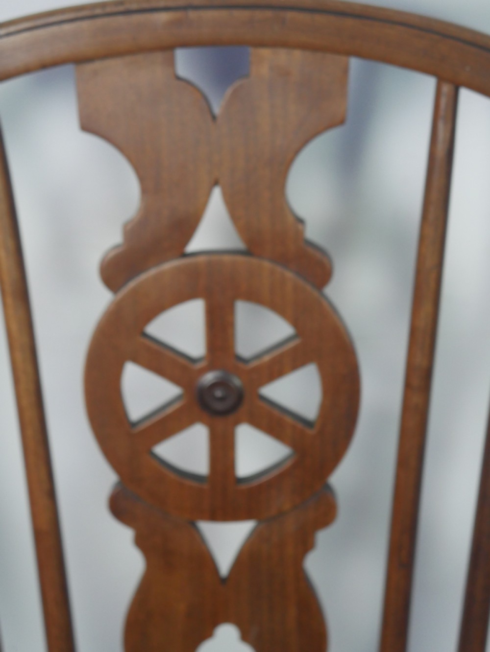 A Regency fruitwood Windsor armchair featuring a hoop back, a pierced wheelback central splat, turned spindles, shaped armrests, a carved saddle seat, and turned legs with stretchers. View VI