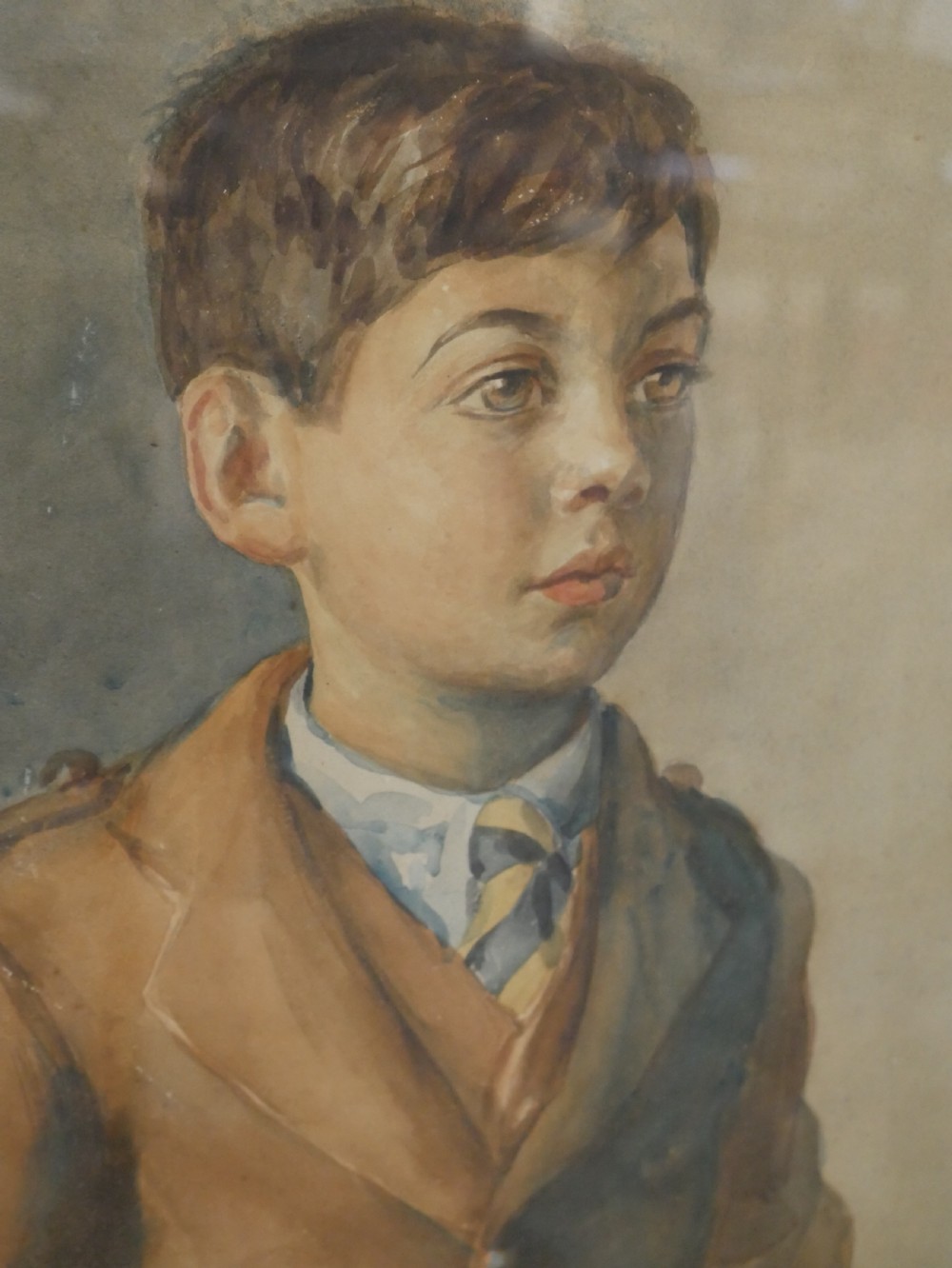 A framed watercolour portrait depicting a young boy standing in full Scottish Highland dress with a brown jacket and tartan kilt. View II