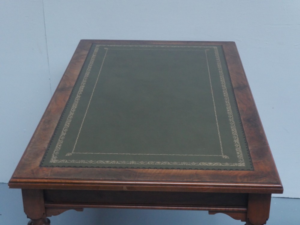 A light walnut writing table featuring a green leather inset top with gilt tooling, a single frieze drawer, and turned fluted legs on brass castors. View VI