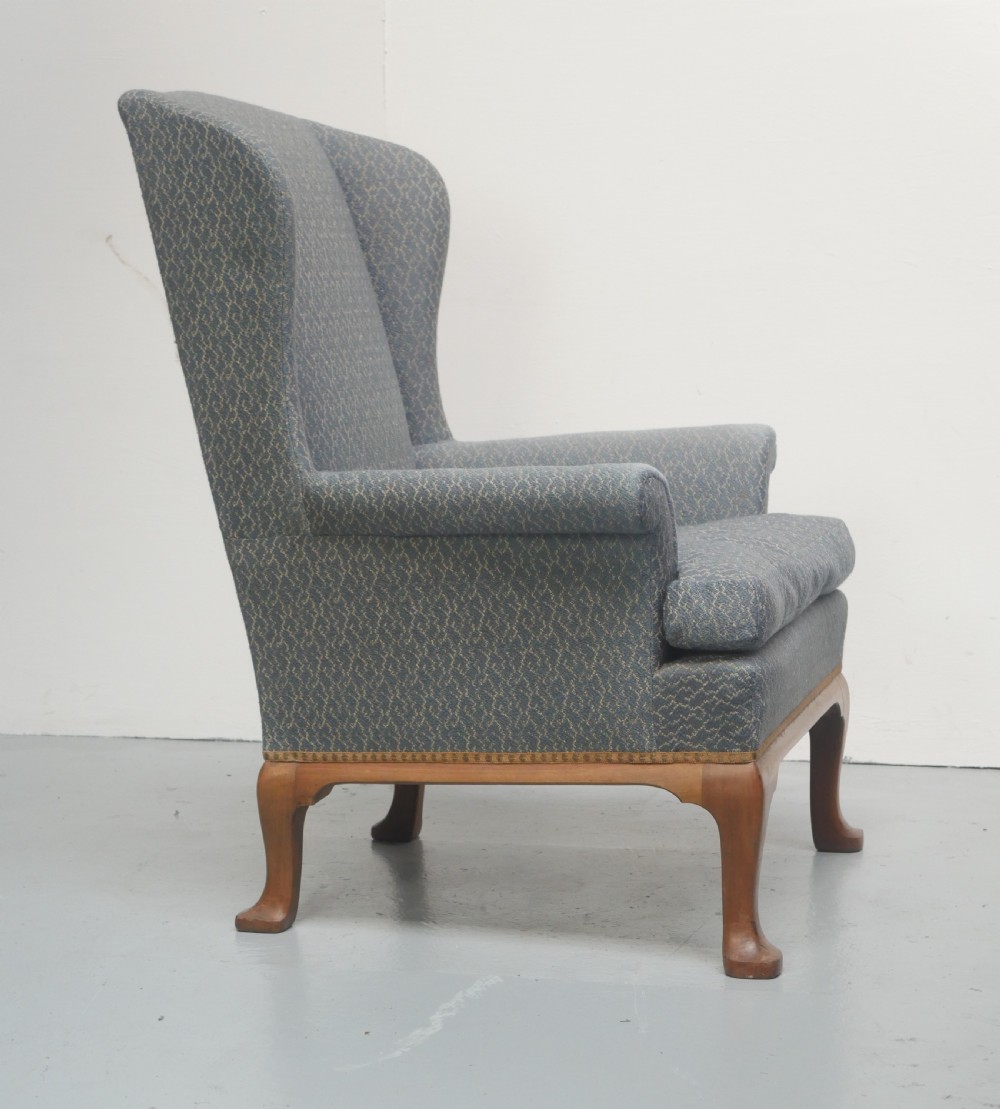 A high-backed wingback armchair upholstered in slate blue patterned fabric, featuring scrolled armrests and wooden cabriole legs. View V