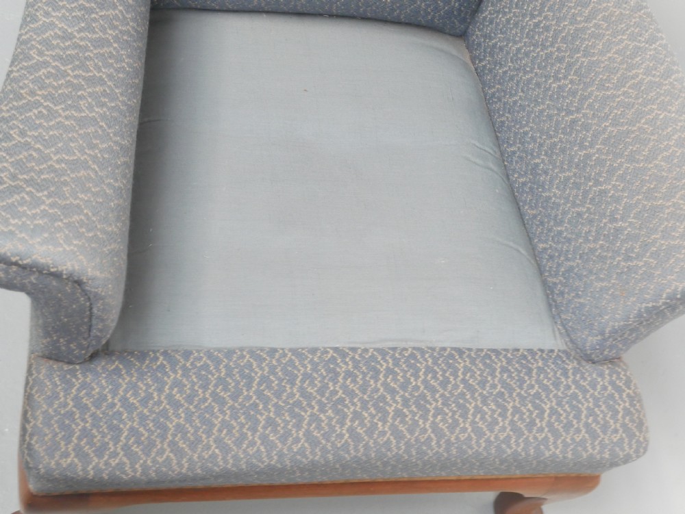 A high-backed wingback armchair upholstered in slate blue patterned fabric, featuring scrolled armrests and wooden cabriole legs. View VI