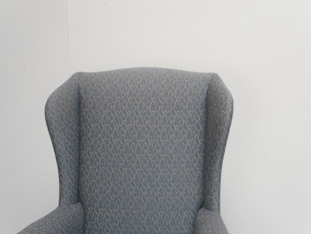 A high-backed wingback armchair upholstered in slate blue patterned fabric, featuring scrolled armrests and wooden cabriole legs. View IX