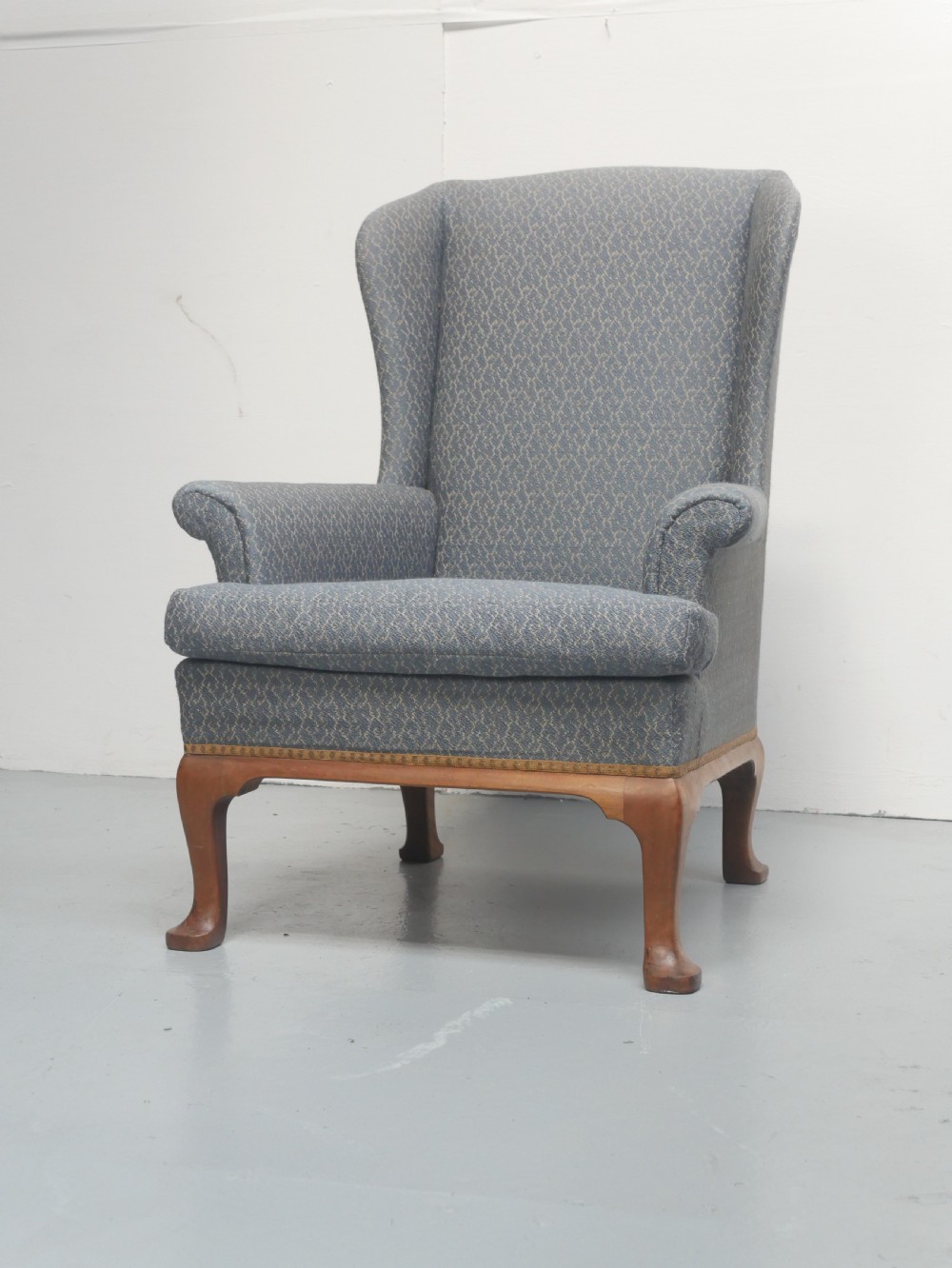 A high-backed wingback armchair upholstered in slate blue patterned fabric, featuring scrolled armrests and wooden cabriole legs. View XII