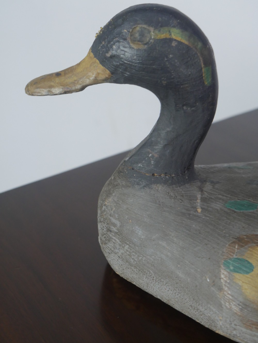 A hand-carved painted wooden decoy duck featuring a dark head and a grey and ochre body. View II