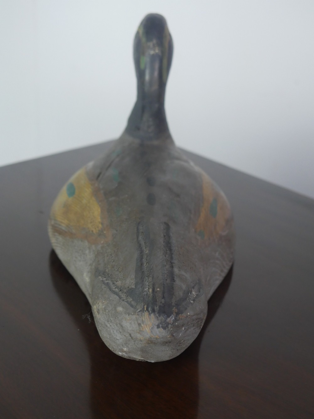 A hand-carved painted wooden decoy duck featuring a dark head and a grey and ochre body. View IV