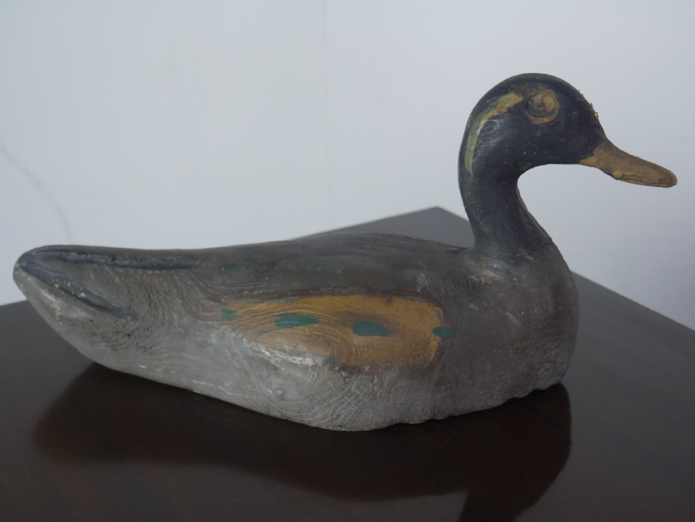 A hand-carved painted wooden decoy duck featuring a dark head and a grey and ochre body. View V