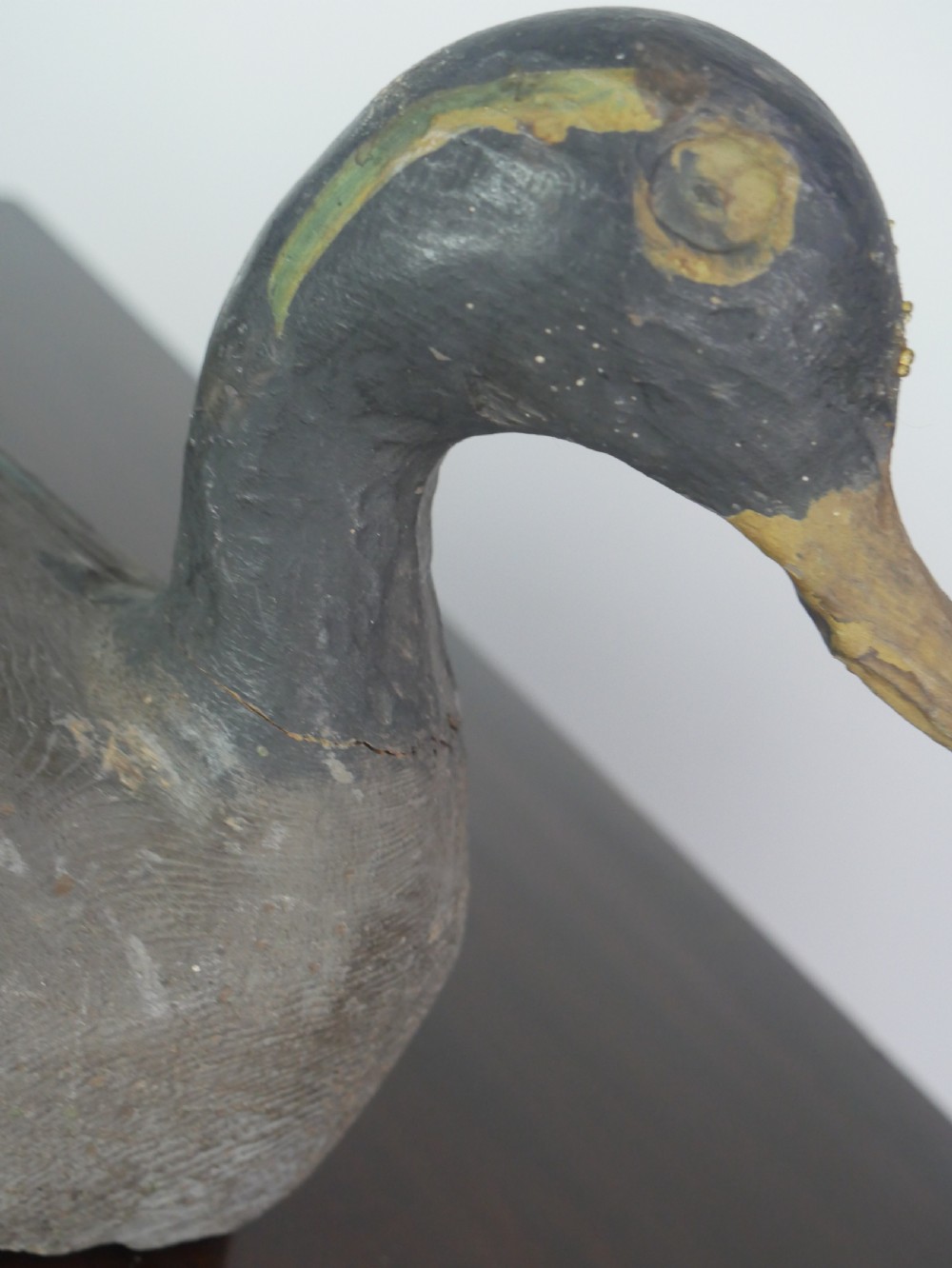 A hand-carved painted wooden decoy duck featuring a dark head and a grey and ochre body. View VI