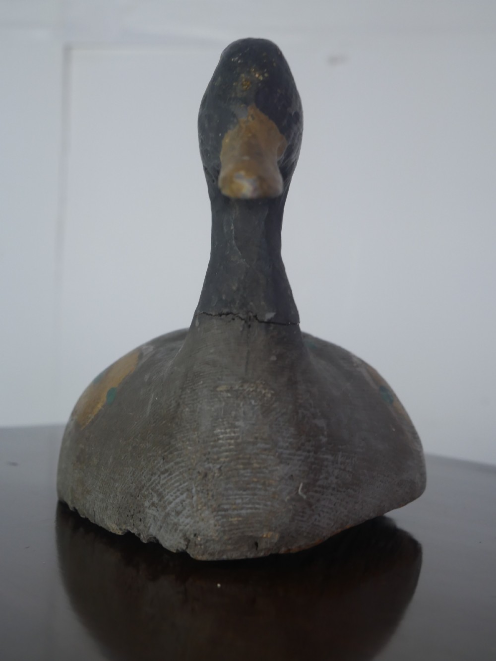 A hand-carved painted wooden decoy duck featuring a dark head and a grey and ochre body. View VII