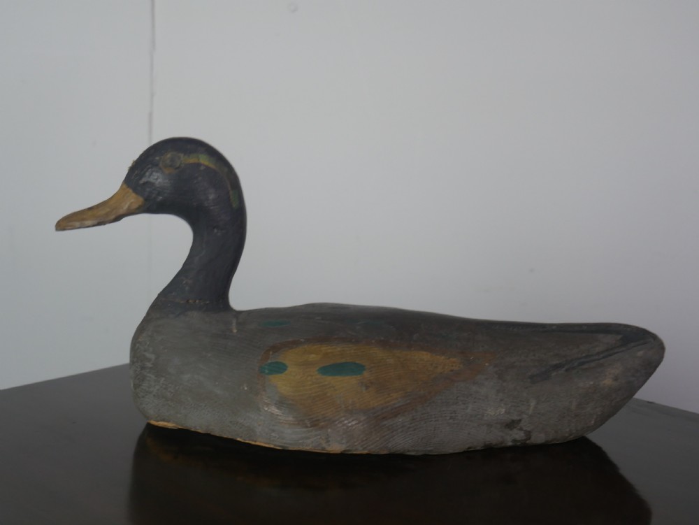 A hand-carved painted wooden decoy duck featuring a dark head and a grey and ochre body. View VIII