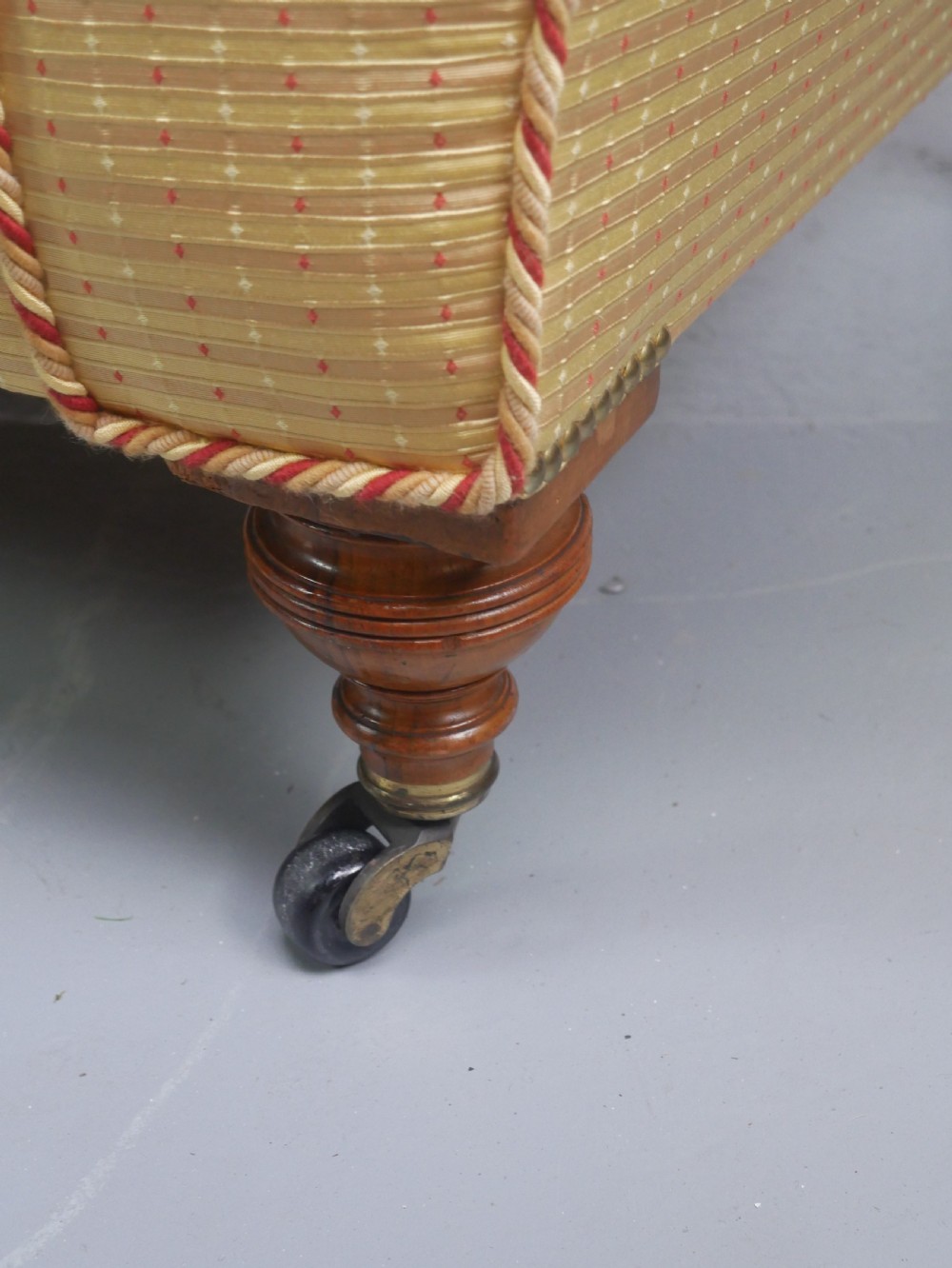 A 19th-century Victorian chaise longue upholstered in a yellow patterned fabric with deep buttoning on the curved backrest and turned mahogany legs on brass castors. View VIII