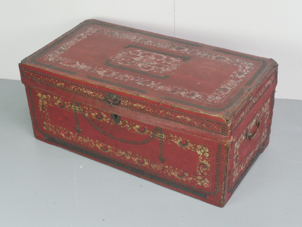 A rectangular red leather China trade trunk decorated with brass studs, brass side handles, and hand-painted gold floral motifs. View II