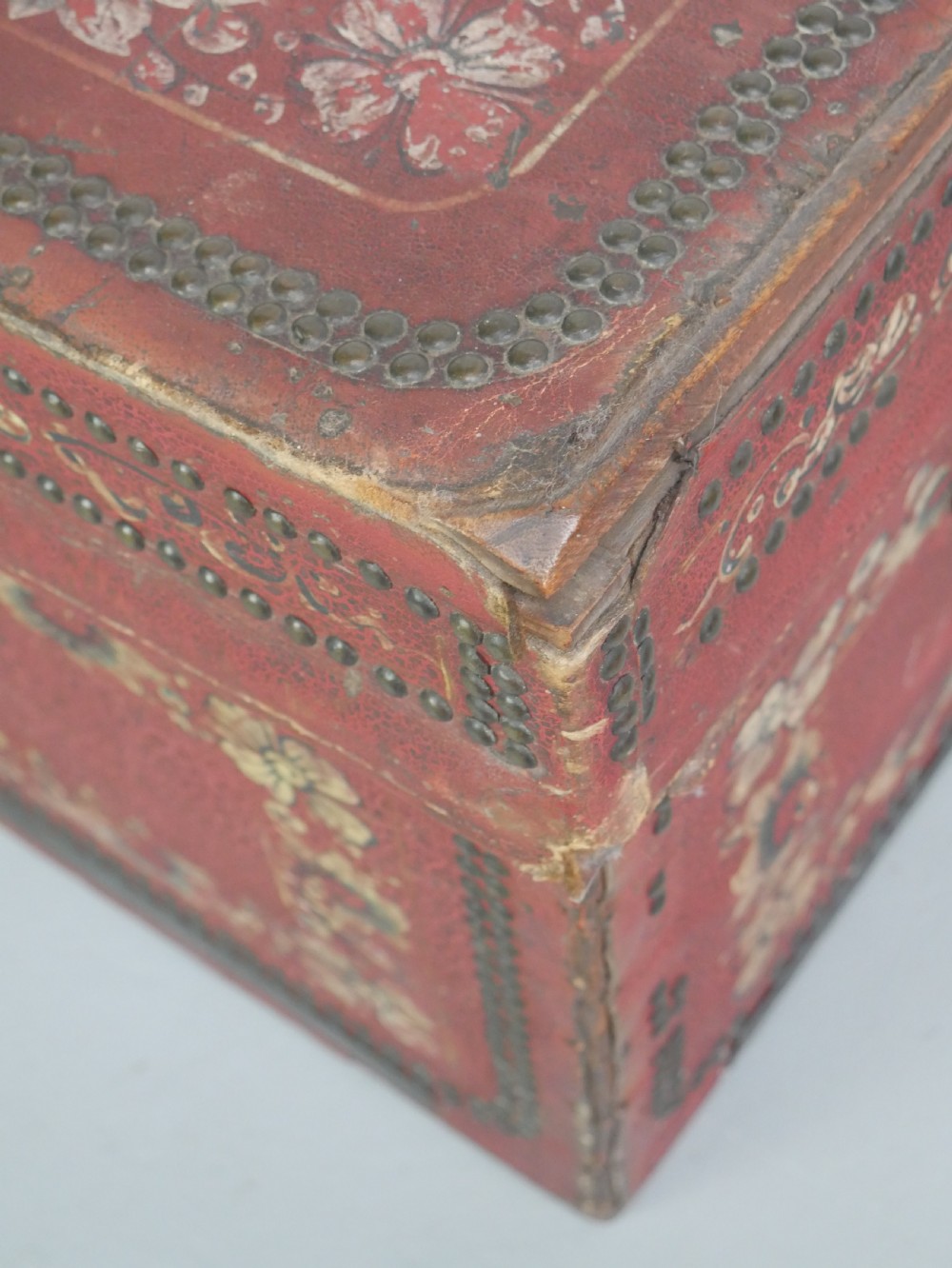A rectangular red leather China trade trunk decorated with brass studs, brass side handles, and hand-painted gold floral motifs. View VIII