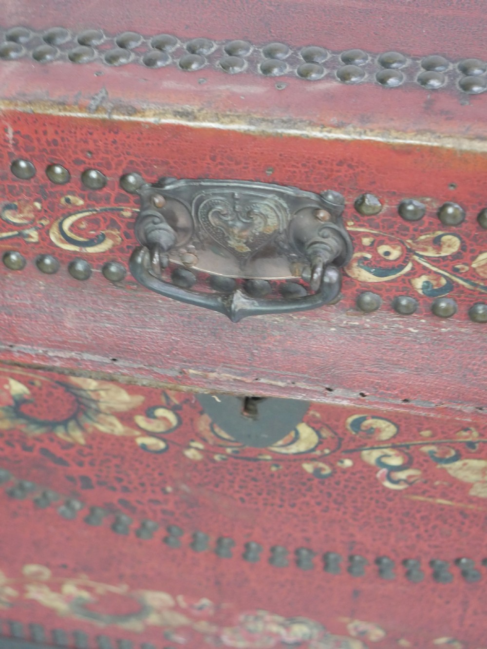 A rectangular red leather China trade trunk decorated with brass studs, brass side handles, and hand-painted gold floral motifs. View XI