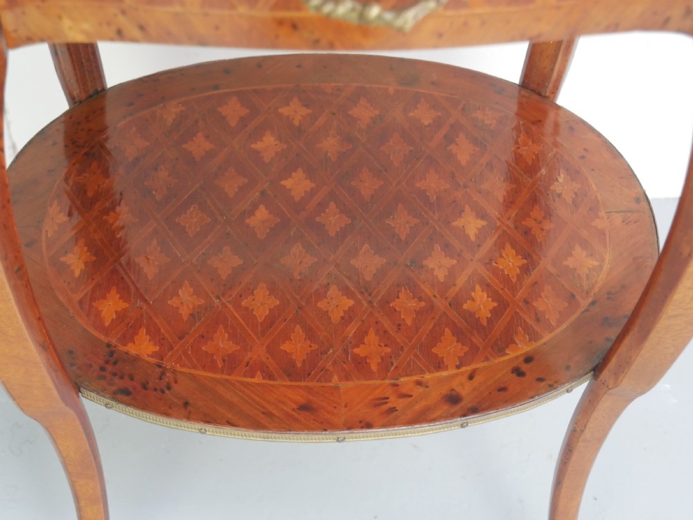 An oval Louis XV style wooden centre table featuring geometric parquetry inlay, a single drawer, a lower tier, cabriole legs, and ornate gilt metal mounts. View III
