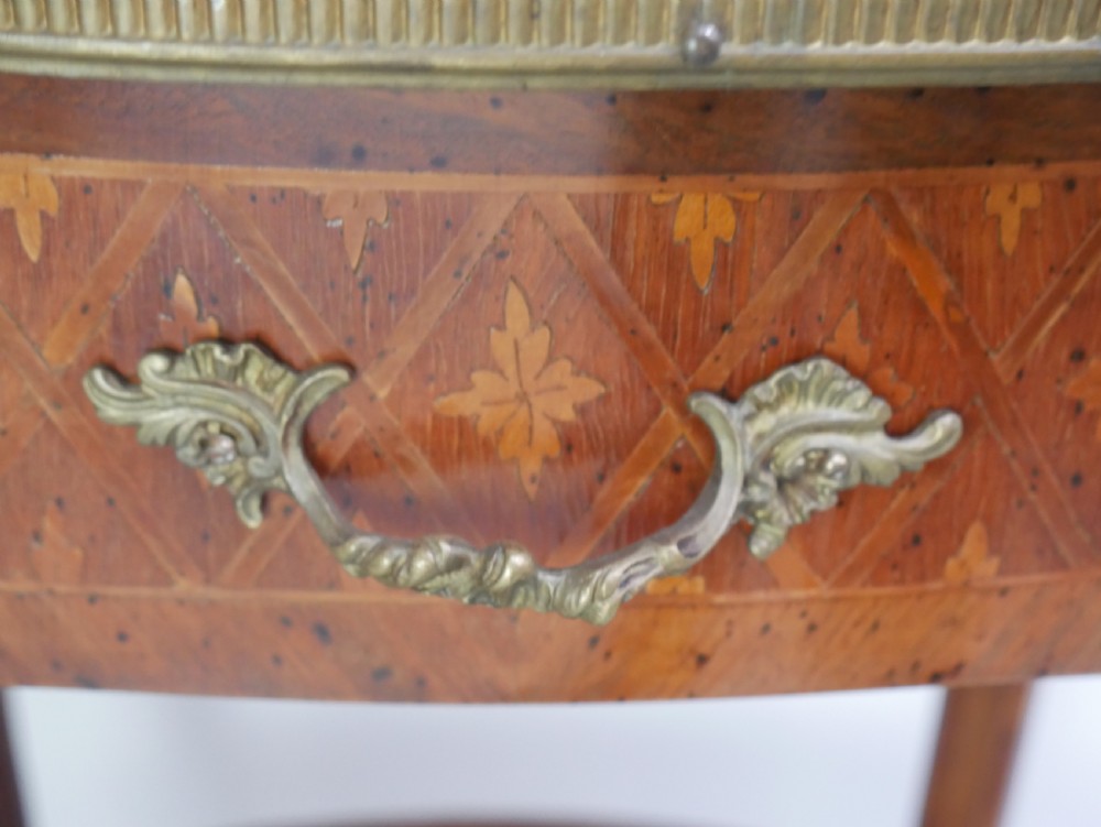 An oval Louis XV style wooden centre table featuring geometric parquetry inlay, a single drawer, a lower tier, cabriole legs, and ornate gilt metal mounts. View VI
