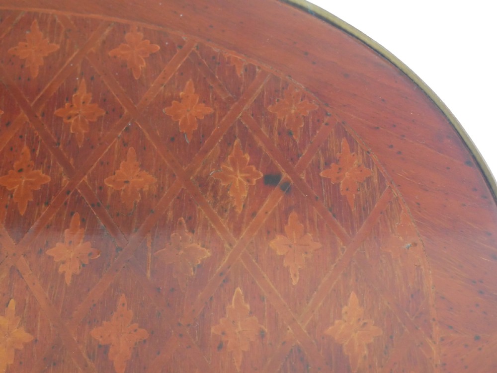 An oval Louis XV style wooden centre table featuring geometric parquetry inlay, a single drawer, a lower tier, cabriole legs, and ornate gilt metal mounts. View VII