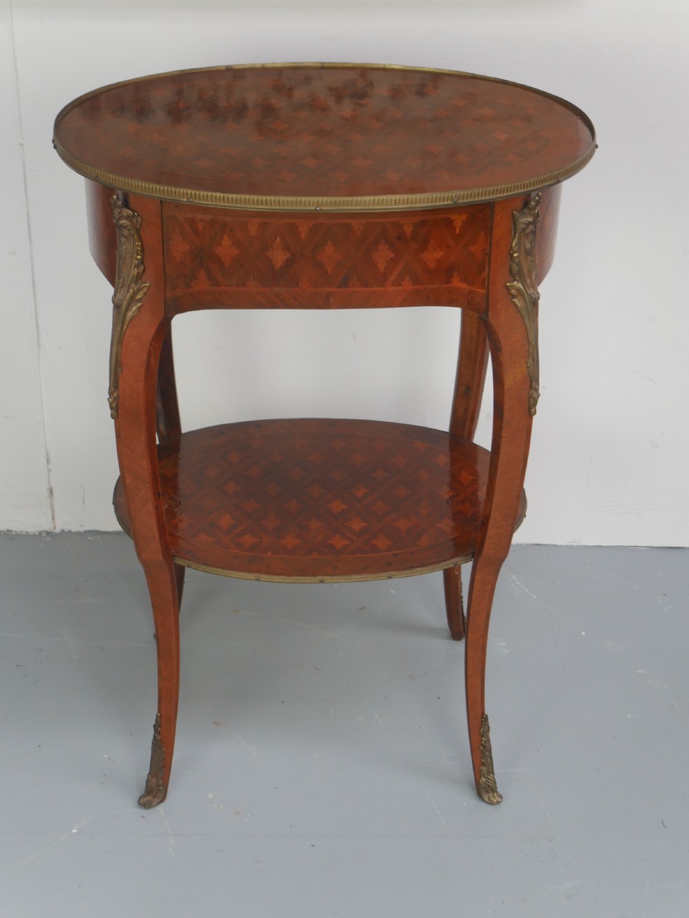 An oval Louis XV style wooden centre table featuring geometric parquetry inlay, a single drawer, a lower tier, cabriole legs, and ornate gilt metal mounts. View XI