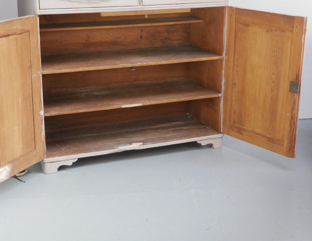 A pale grey painted Scandinavian cupboard featuring two carved drawers above two diamond-panelled doors with brass hardware. View VIII
