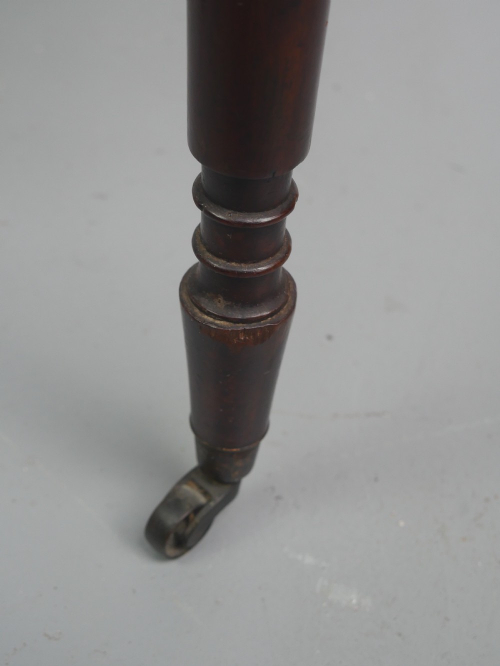 A dark mahogany Regency side table featuring a single drawer with turned knobs, a central brass keyhole, and turned legs terminating in castors. View IX