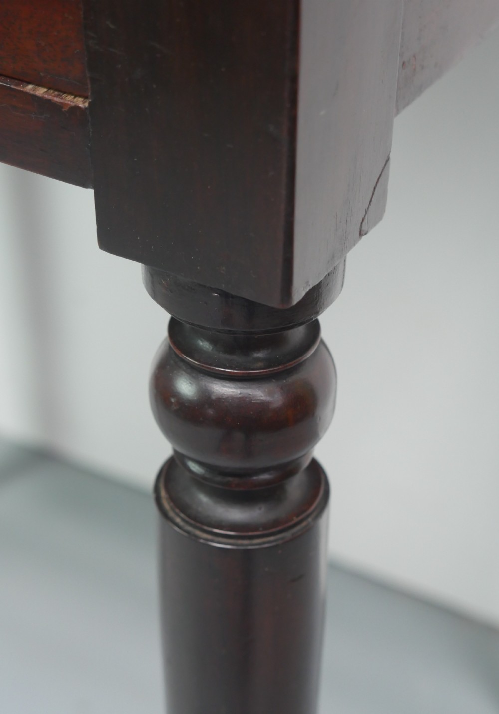 A dark mahogany Regency side table featuring a single drawer with turned knobs, a central brass keyhole, and turned legs terminating in castors. View XIII