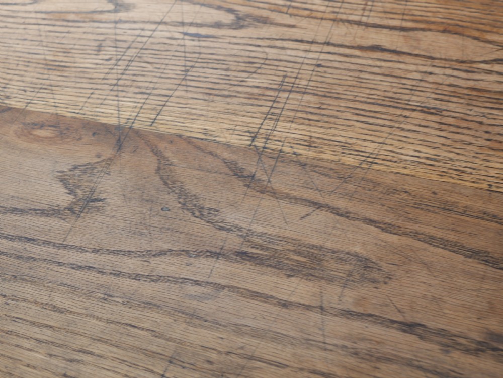 A long solid oak refectory dining table featuring a plank top, shaped trestle end supports, and a central pegged stretcher. View IX