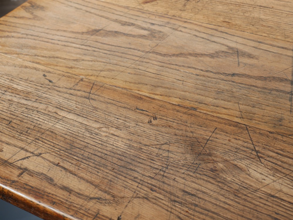 A long solid oak refectory dining table featuring a plank top, shaped trestle end supports, and a central pegged stretcher. View X