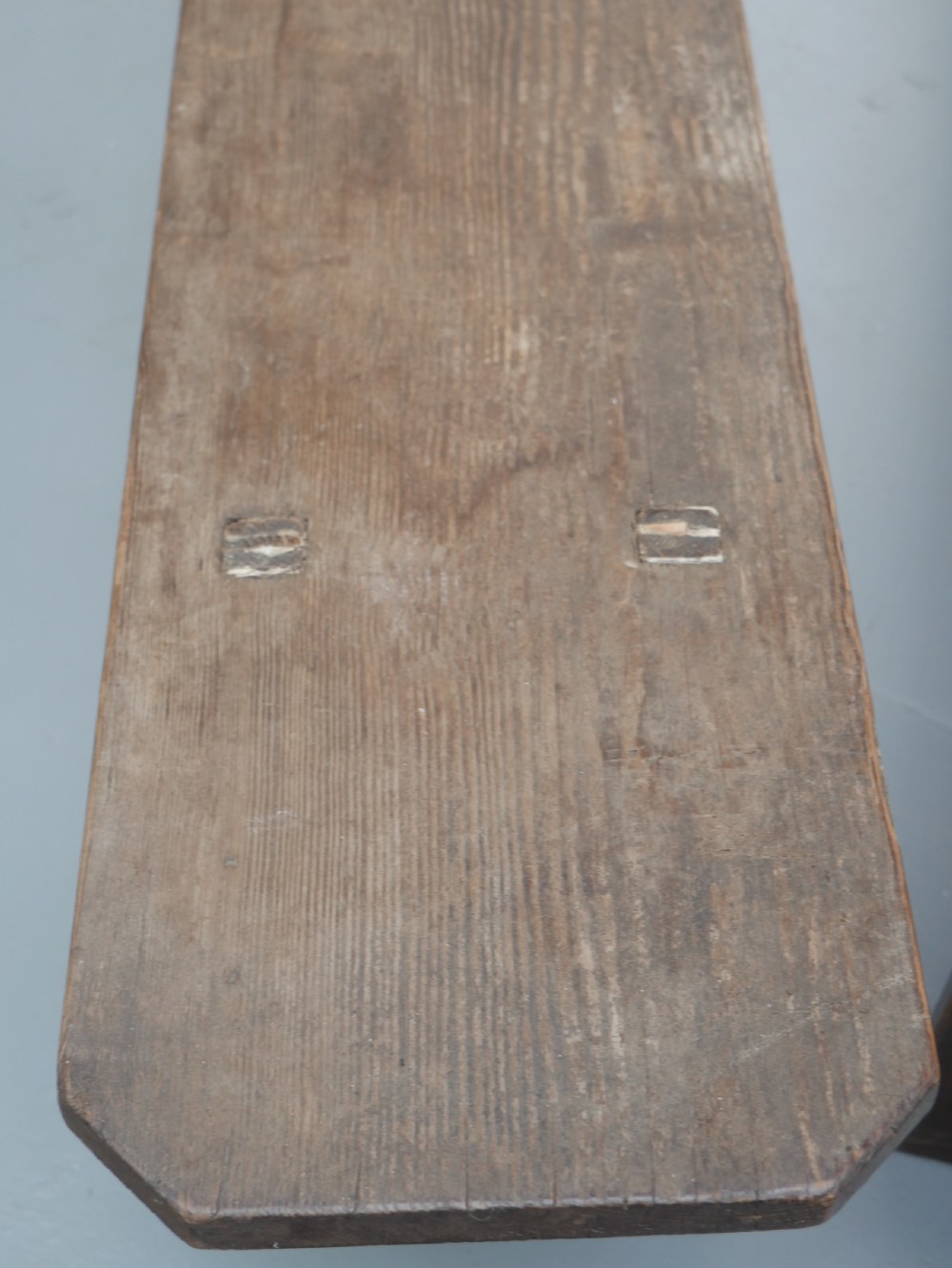 A pair of long, dark brown rustic pine benches featuring solid plank tops and trestle-style slab legs with arched cutouts. View III