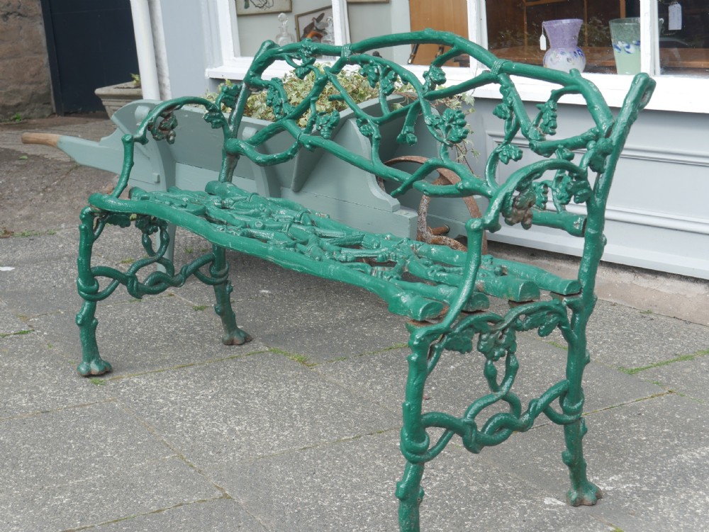 A green painted Victorian cast iron garden bench featuring a naturalistic organic branch and twig pattern. View II
