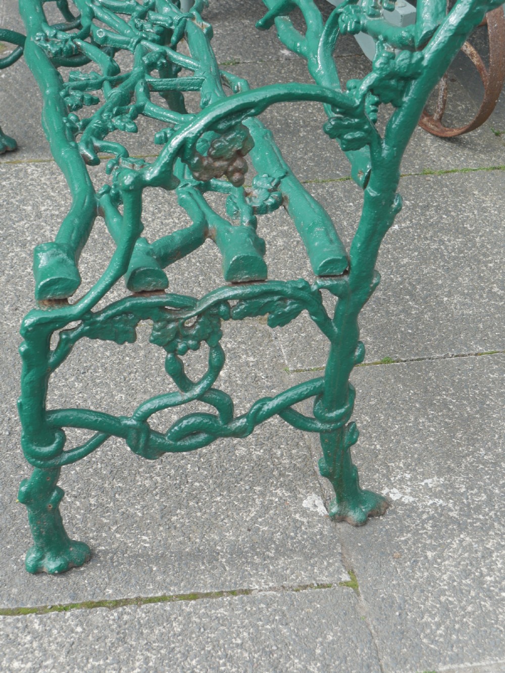 A green painted Victorian cast iron garden bench featuring a naturalistic organic branch and twig pattern. View III