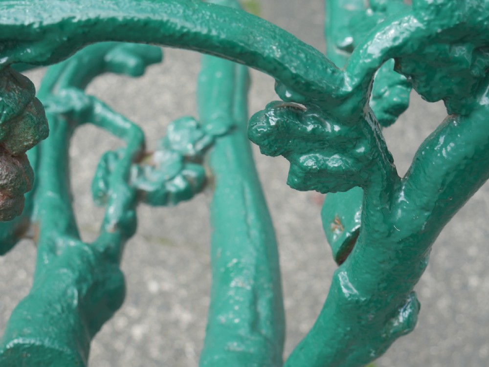 A green painted Victorian cast iron garden bench featuring a naturalistic organic branch and twig pattern. View VI