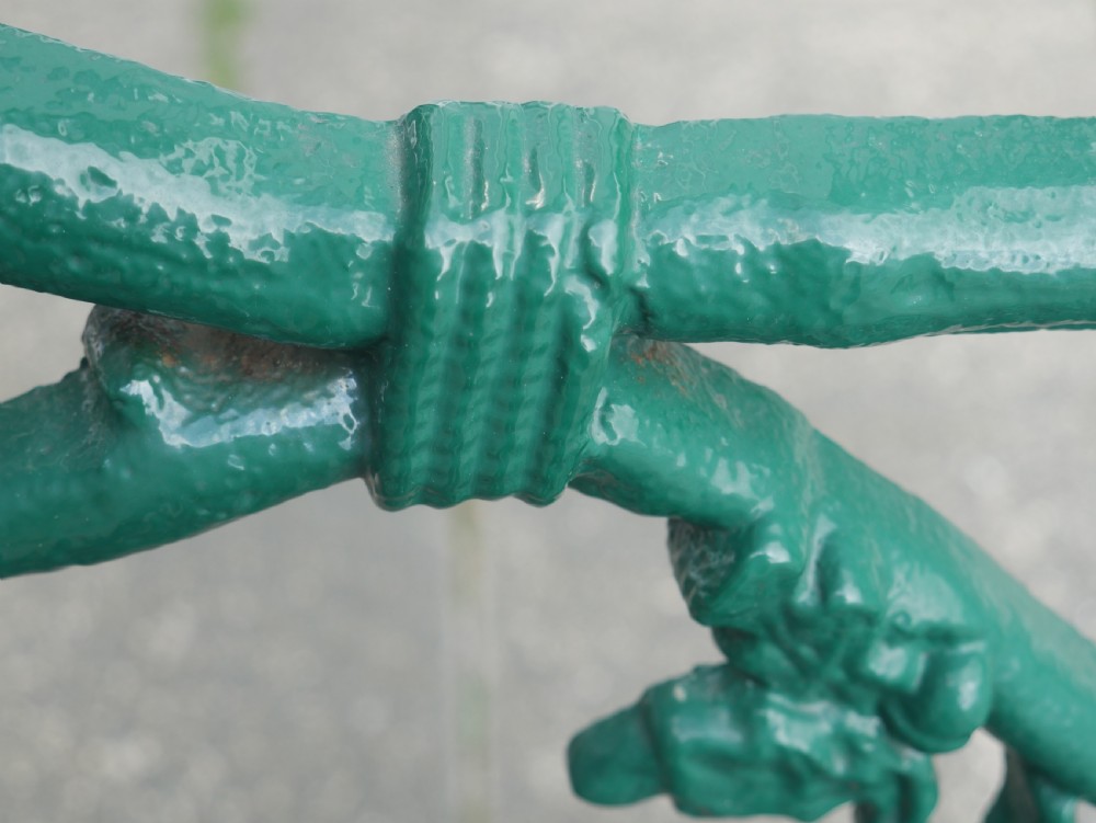 A green painted Victorian cast iron garden bench featuring a naturalistic organic branch and twig pattern. View VII