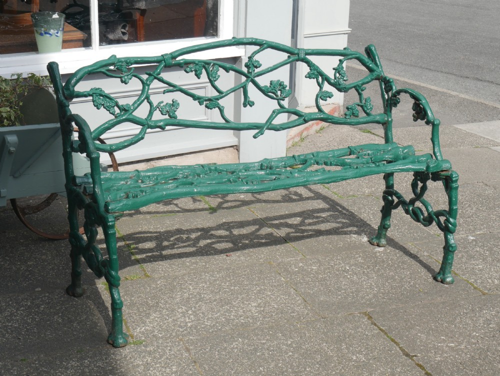 A green painted Victorian cast iron garden bench featuring a naturalistic organic branch and twig pattern. View X