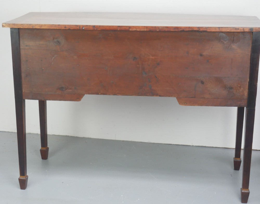 A small Georgian bowfront mahogany sideboard featuring an arched central apron, two side drawers with oval brass handles, and square tapered legs. View IV