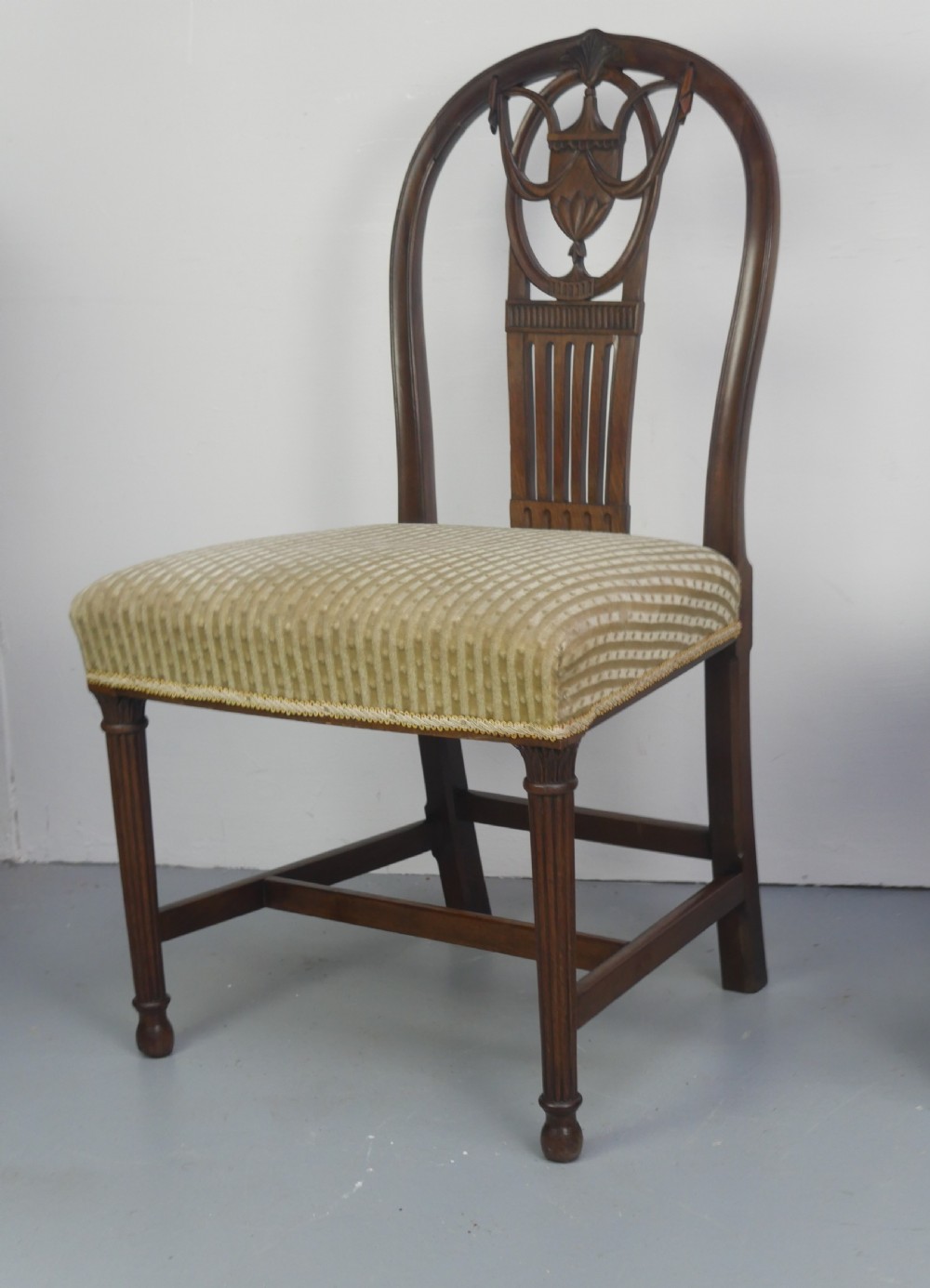 A pair of antique Georgian mahogany side chairs featuring pierced urn carved splats, arched backs, and upholstered seats supported by fluted front legs. View III