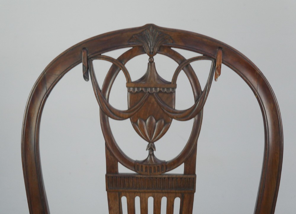 A pair of antique Georgian mahogany side chairs featuring pierced urn carved splats, arched backs, and upholstered seats supported by fluted front legs. View XII