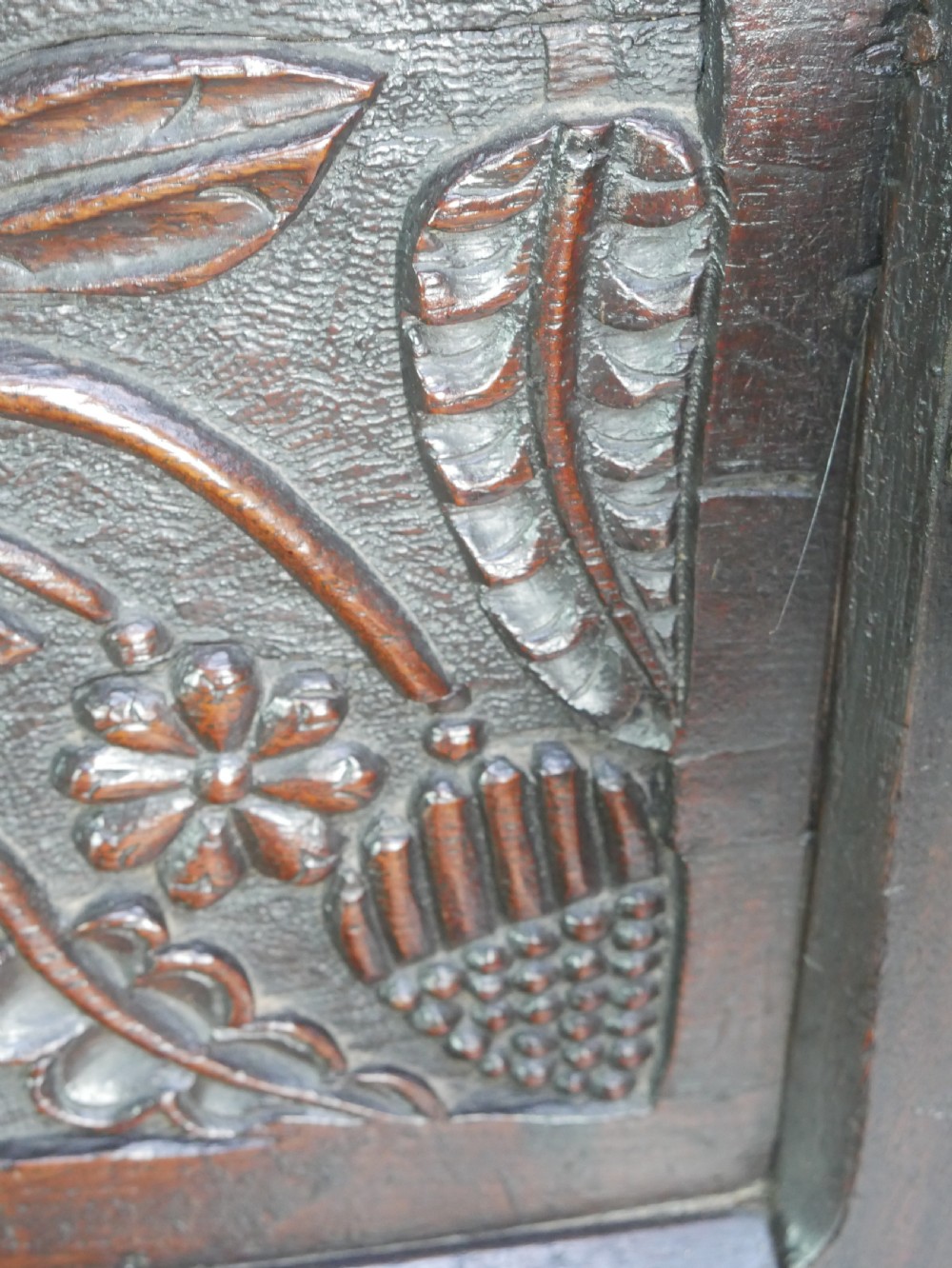 A dark oak 17th-century wainscot armchair featuring a relief-carved back panel, turned front legs, and flat armrests. View VI