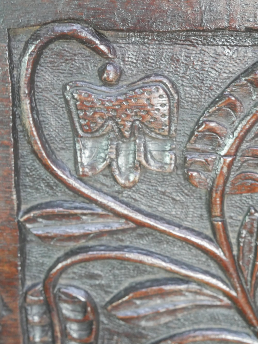 A dark oak 17th-century wainscot armchair featuring a relief-carved back panel, turned front legs, and flat armrests. View VII