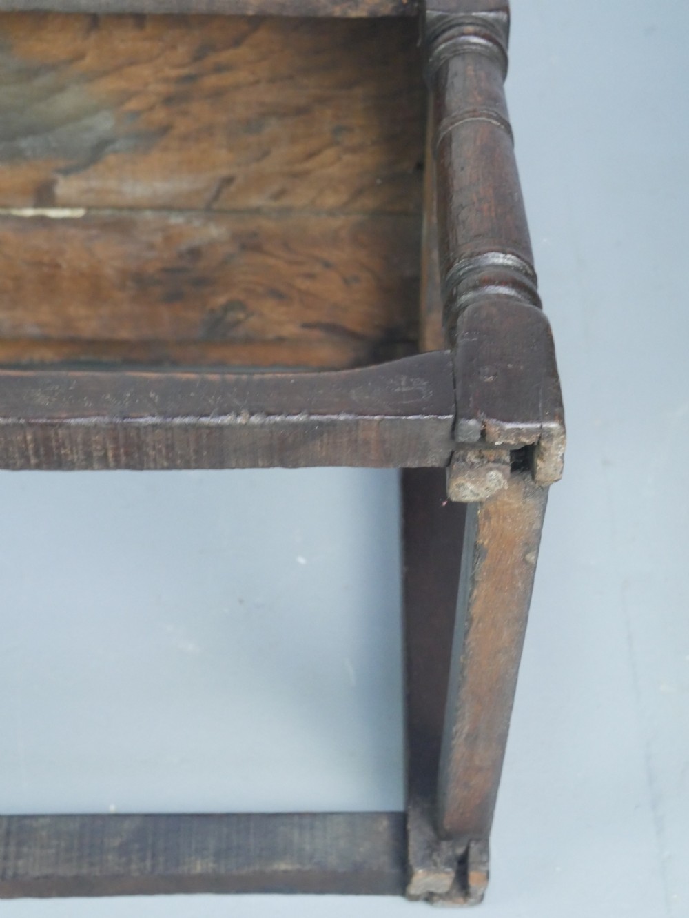 A dark oak 17th-century wainscot armchair featuring a relief-carved back panel, turned front legs, and flat armrests. View XIV