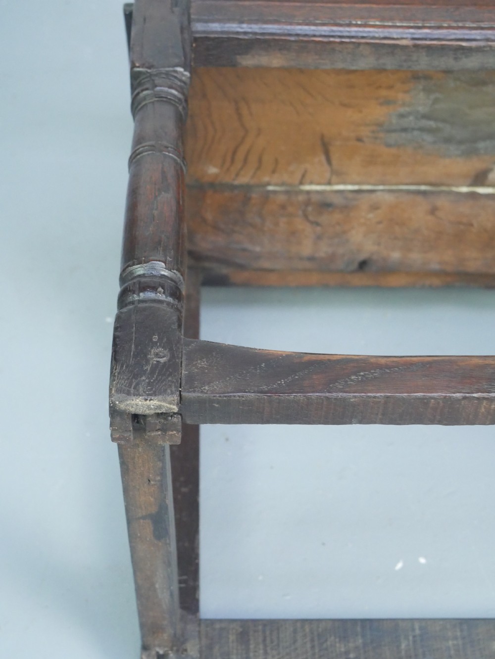 A dark oak 17th-century wainscot armchair featuring a relief-carved back panel, turned front legs, and flat armrests. View XVI