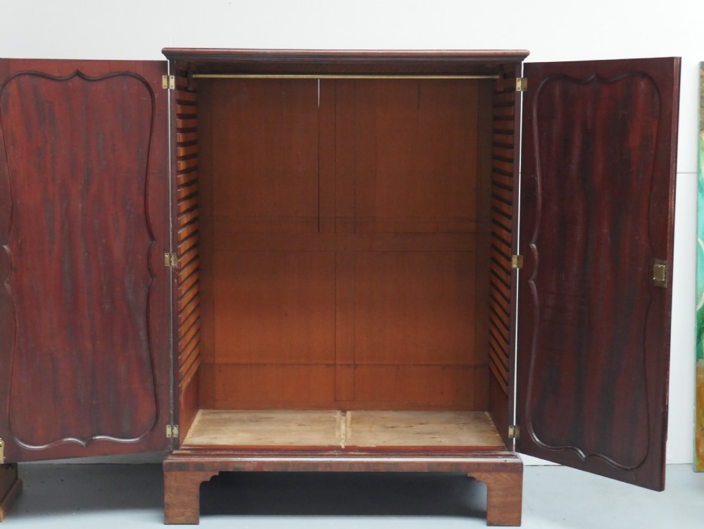 A Georgian mahogany double-door hanging wardrobe featuring shaped curvilinear door panels and sturdy bracket feet. View III