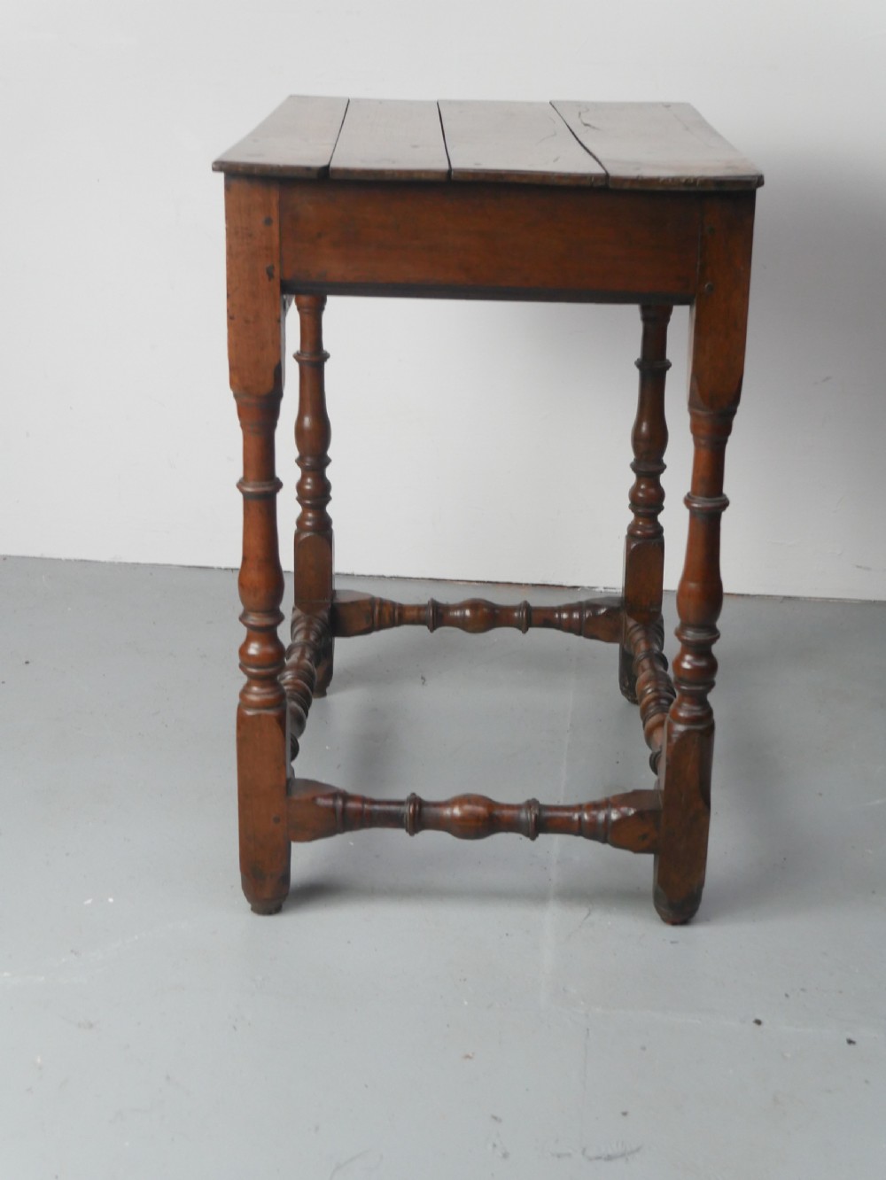 An 18th-century fruitwood side table featuring a single drawer with two brass teardrop handles, slender turned legs, and lower connecting stretchers. View V