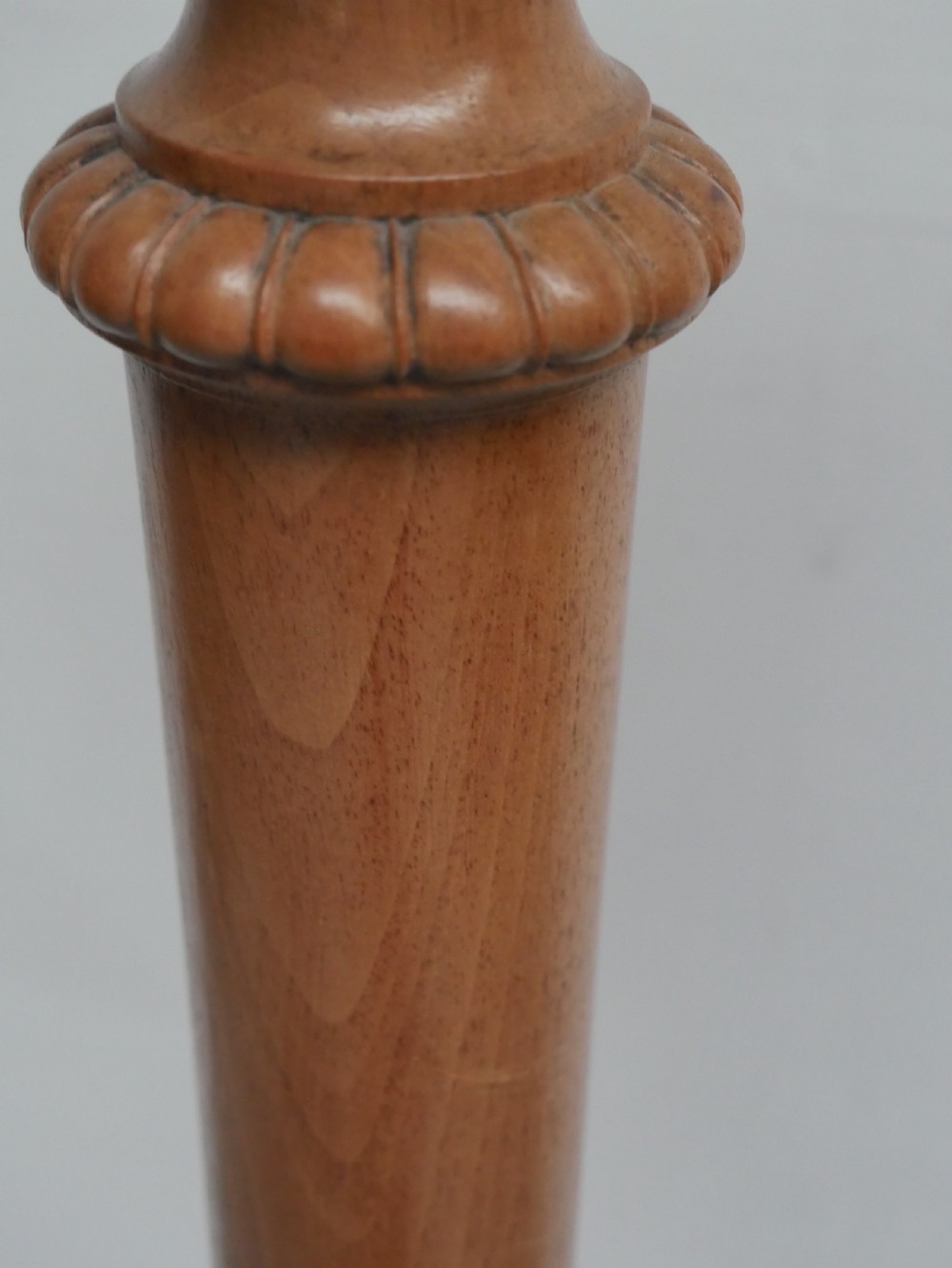 A tall walnut plant stand featuring a carved circular top, turned central column, and tripod base with cabriole legs. View VI