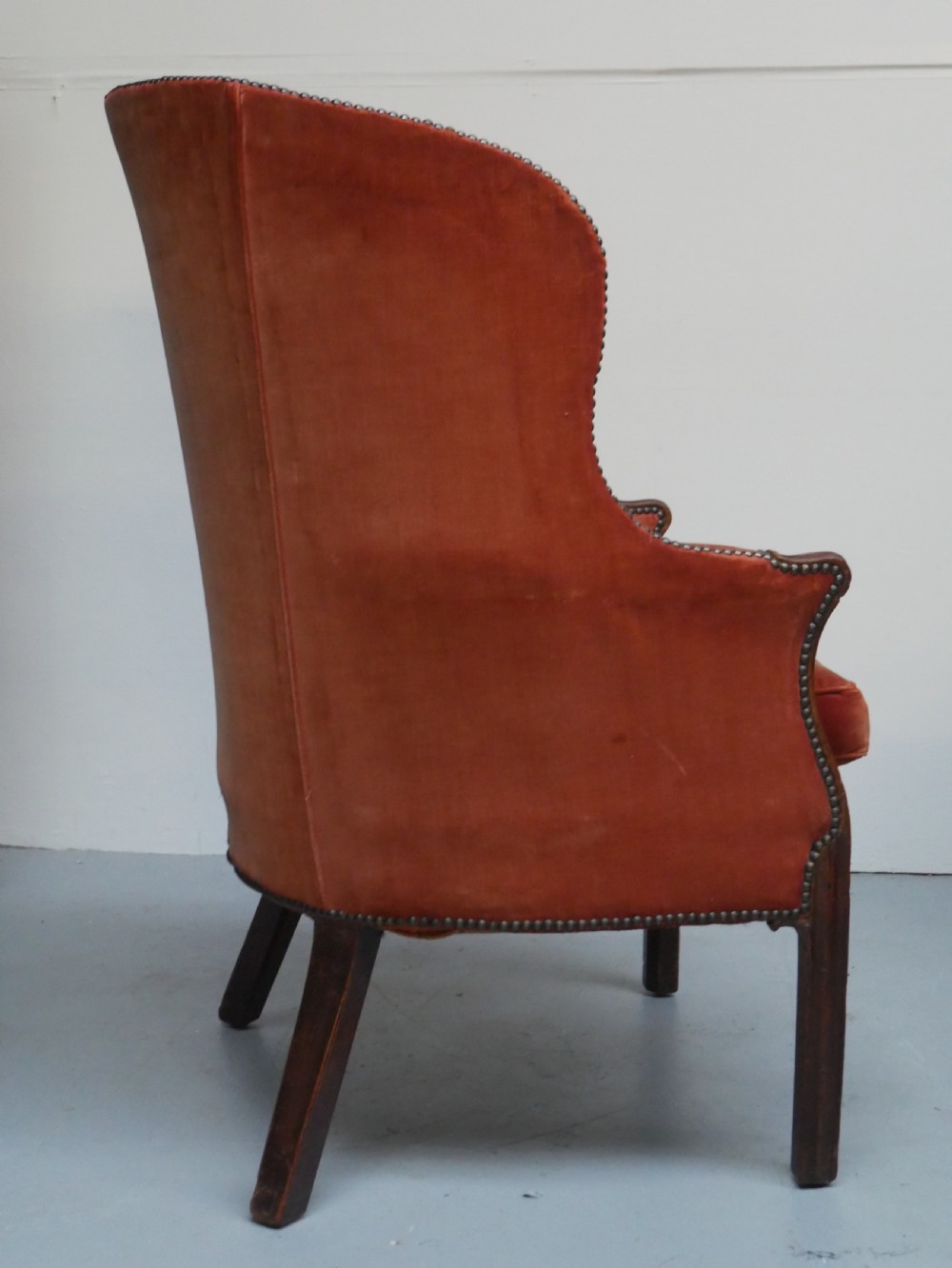 A Georgian high-backed barrel armchair upholstered in burnt orange velvet with brass stud trimming and dark mahogany legs. View V