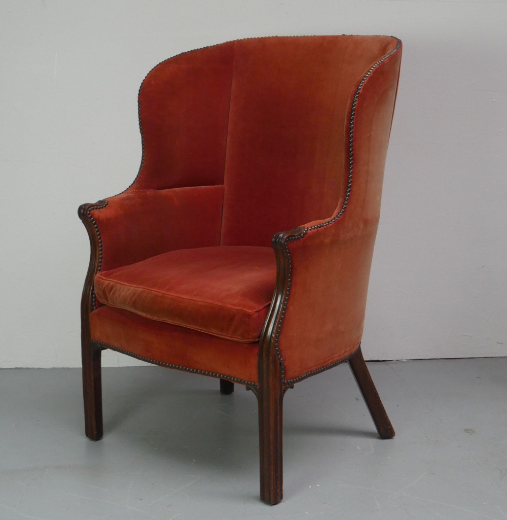 A Georgian high-backed barrel armchair upholstered in burnt orange velvet with brass stud trimming and dark mahogany legs. View IV